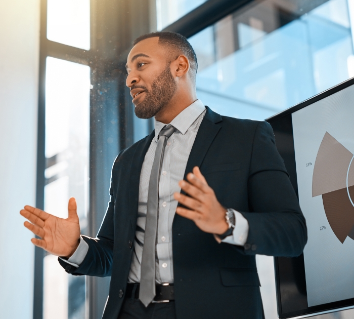 man standing in front of graph doing a presentation