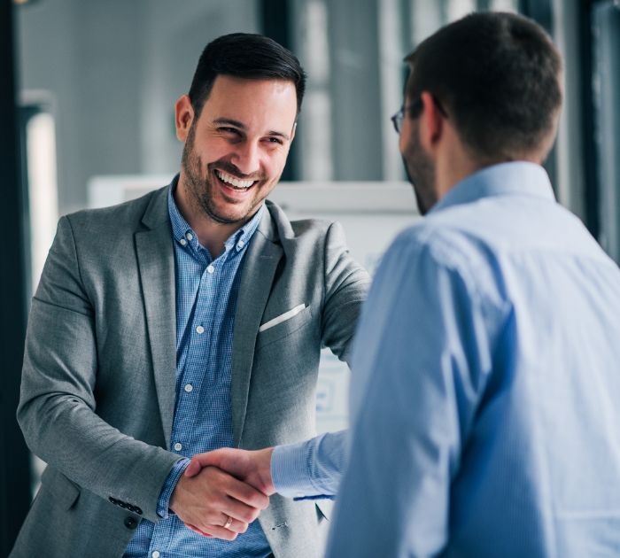 Two men shaking hands and smiling for some reason