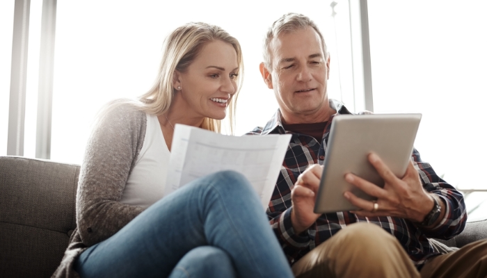 couple looking at paperwork on couch and smiling for some reason